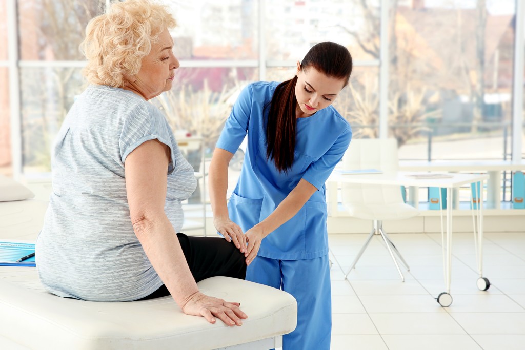 Arthrose Untersuchung Eine Orthopädin untersucht in der Klinik ein Knie älterer Frau