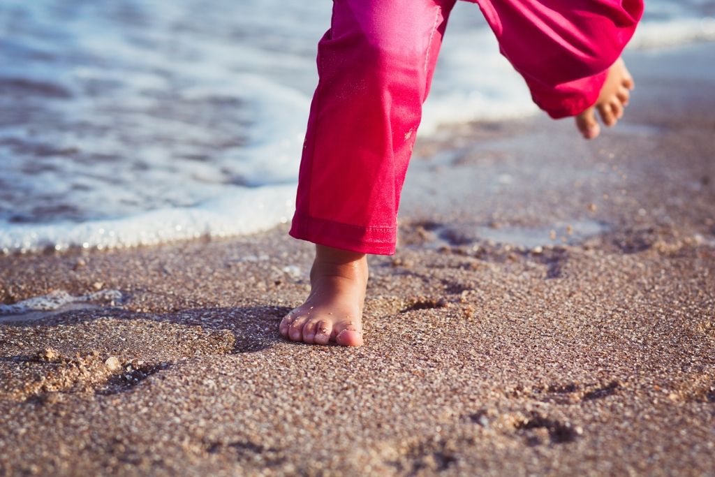 Beine eines Kindes, das am Strand läuft