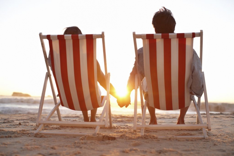 Ein Paar, das auf dem Strand während eines hübschen Sonnenuntergangs sitzt.